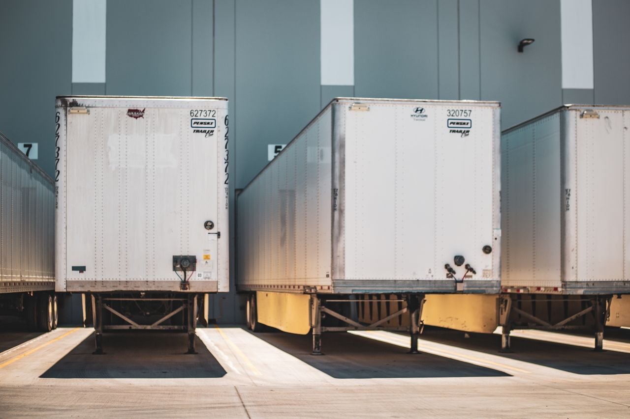Home A row of freight trailers parked at a commercial loading dock, emphasizing transportation and logistics.